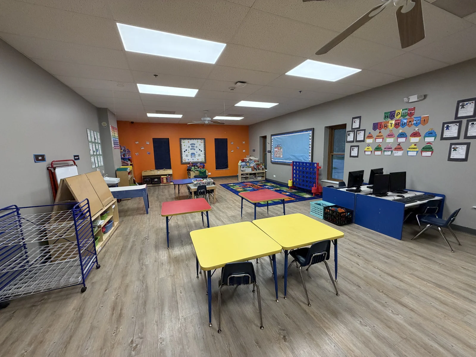 Advanced Pre-K and School Age Room with child-sized tables, computers, classroom displays, learning materials, and activity centers