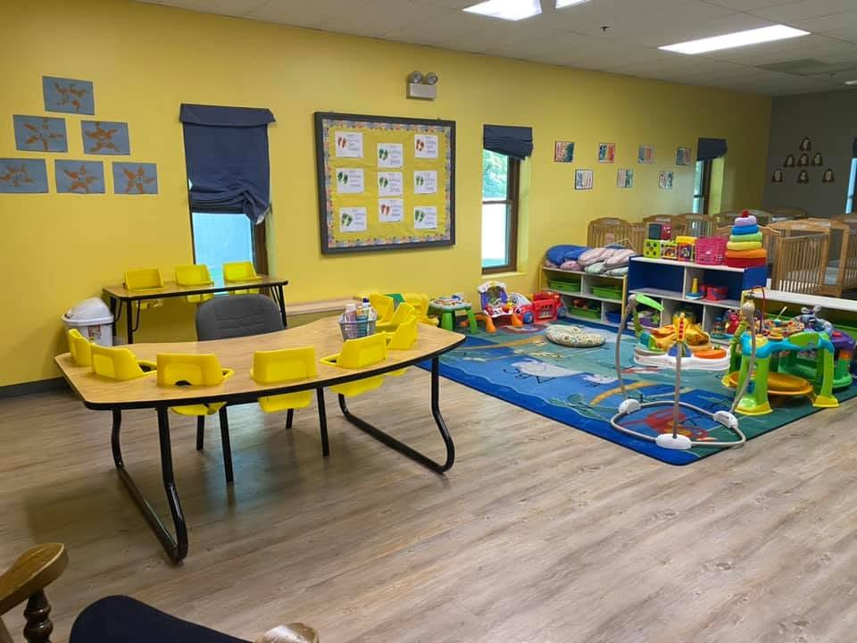 Infant Room activity and feeding areas with child-sized seating, toys, and cribs