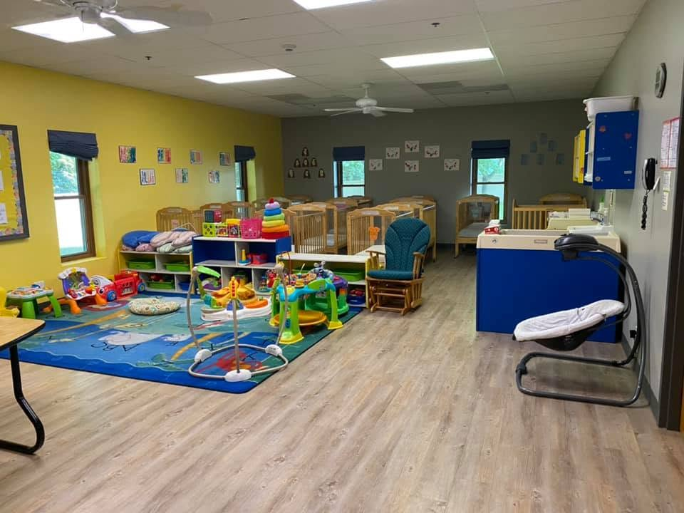 Infant Room play area, cribs, rocking chair, and care station