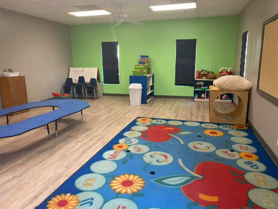 Two-Year-Old Room with a classroom rug, low table, chairs, and toy shelves