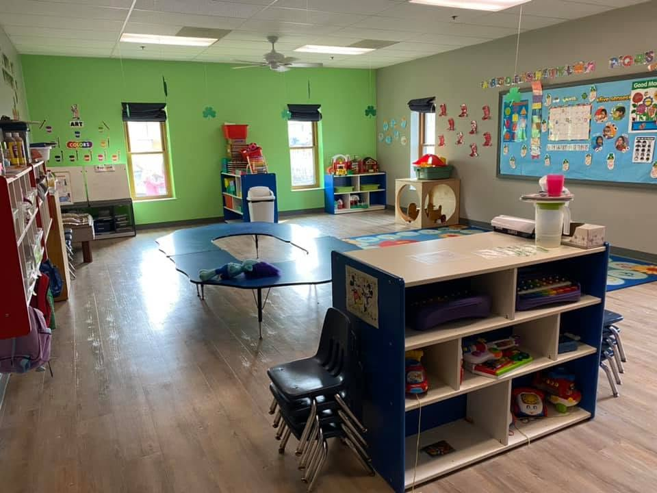 Two-Year-Old Room with learning tables, classroom displays, shelves, and open activity space